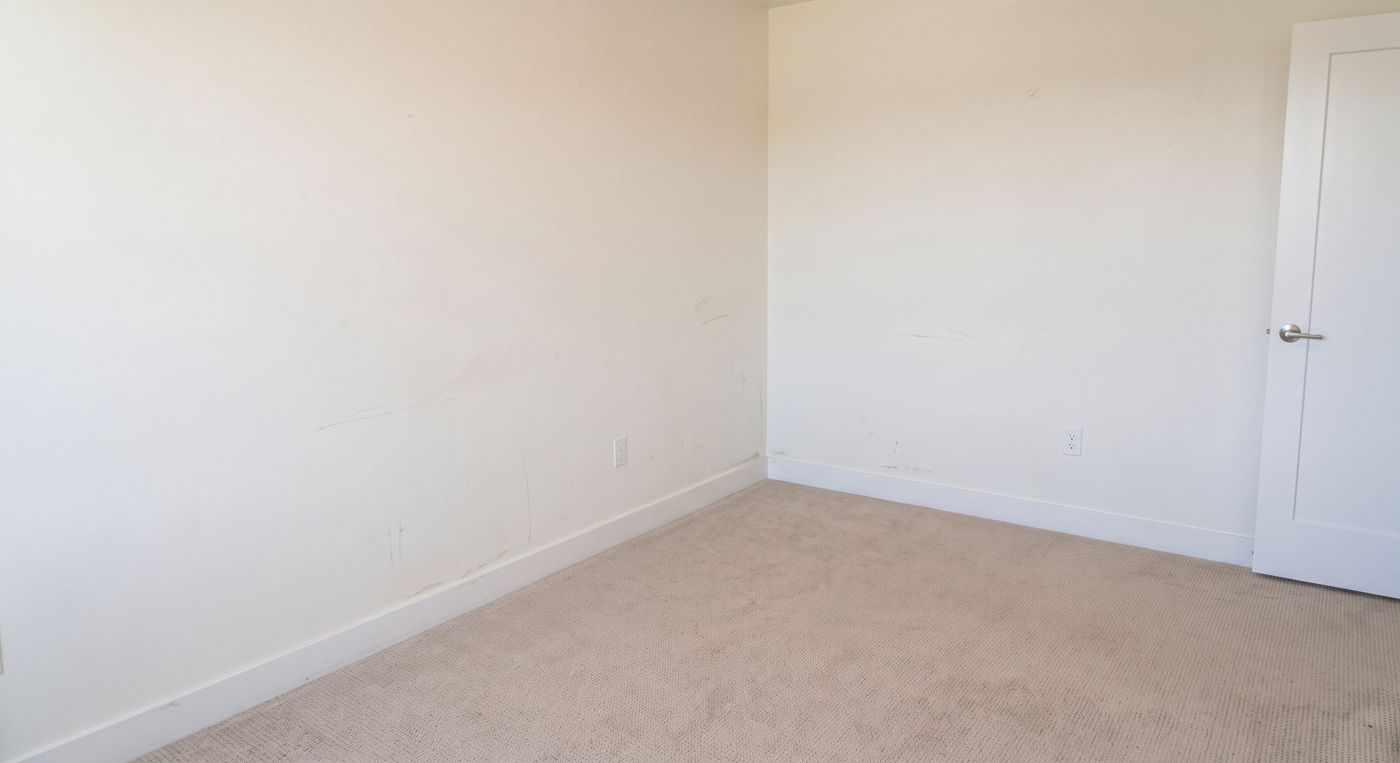 Empty bedroom with dingy walls marked by scuffs and scrapes left behind after move-out